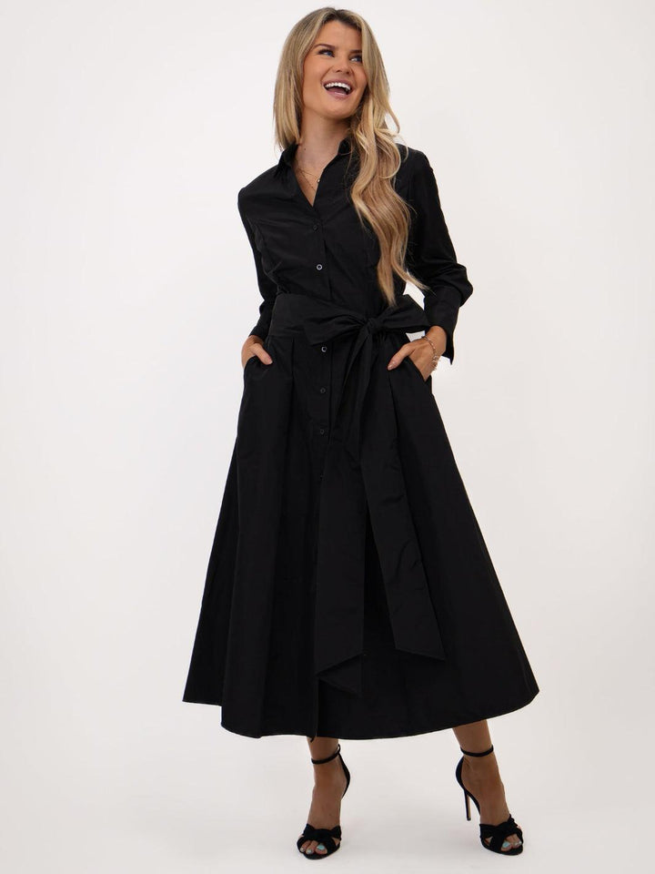 Woman wearing a black dress with a belt on a white background