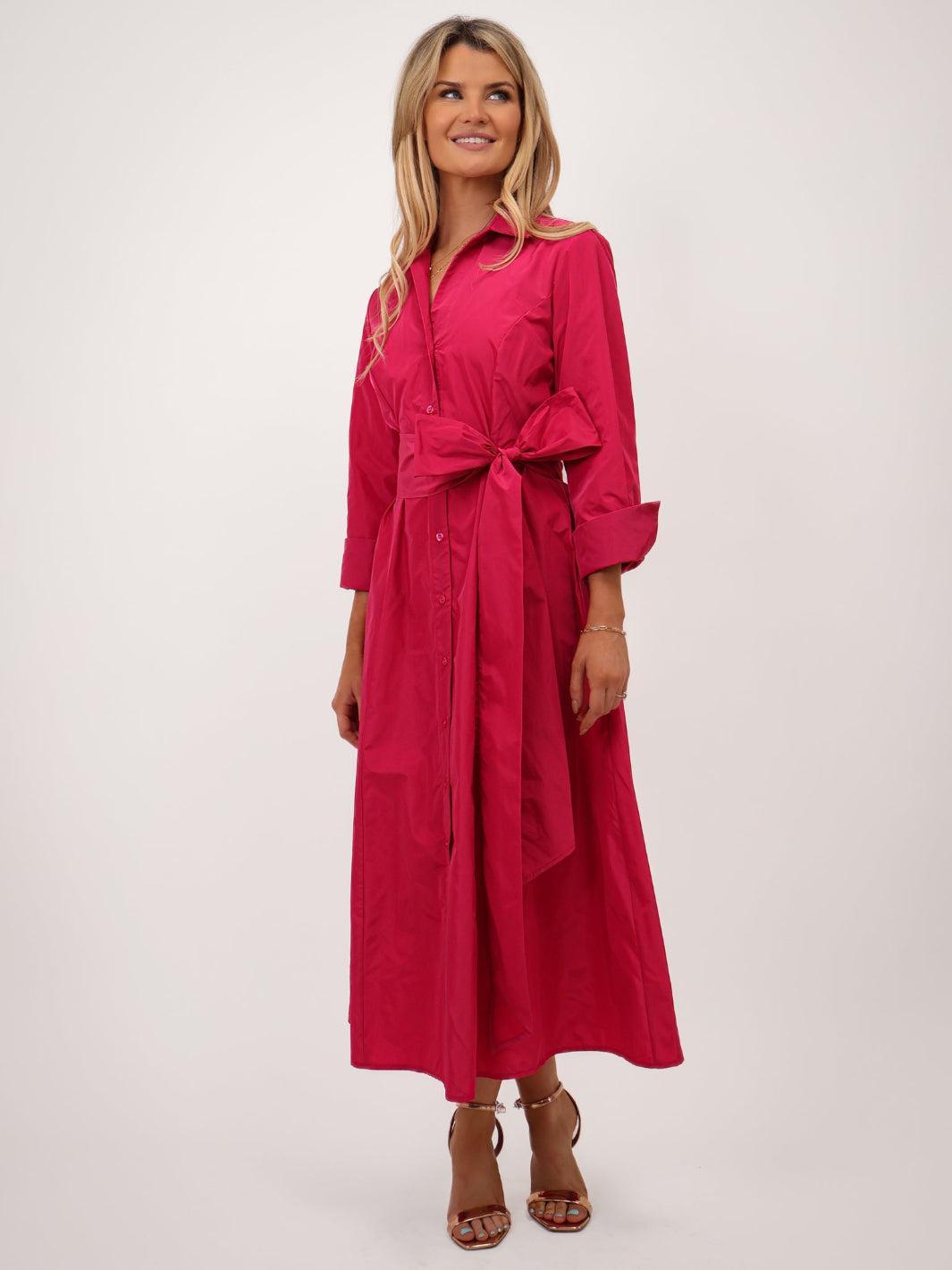 Woman wearing a pink dress with a belt on a white background