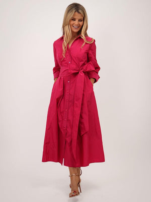 Woman wearing a bright pink dress with a belt on a white background