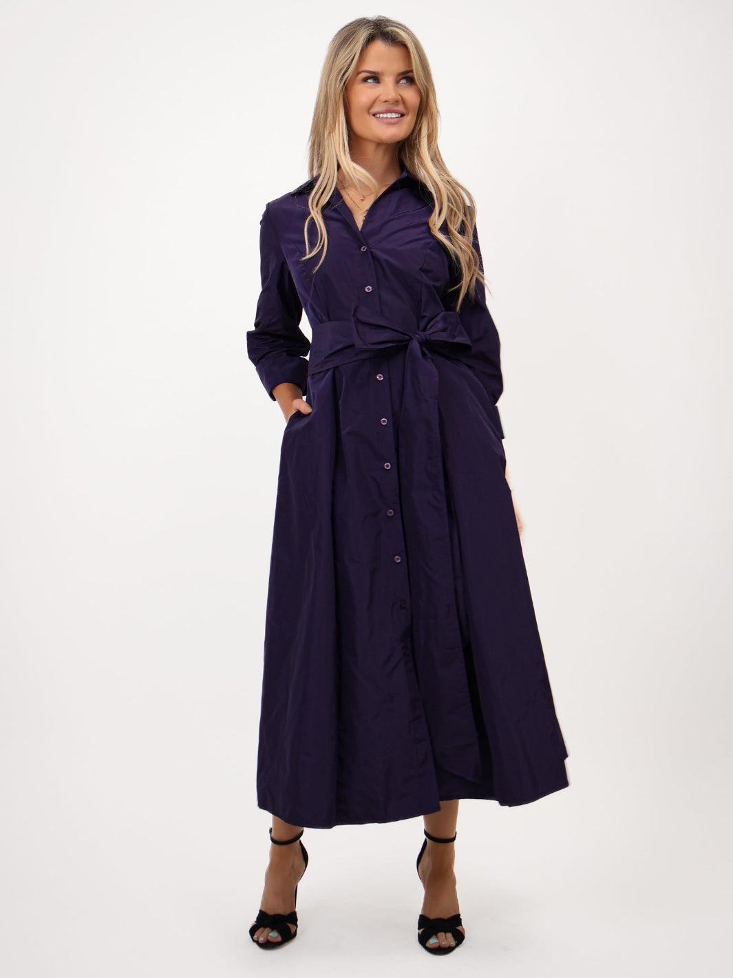 Woman wearing a long dark purple dress on a white background