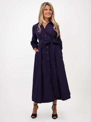 Woman wearing a long dark purple dress on a white background