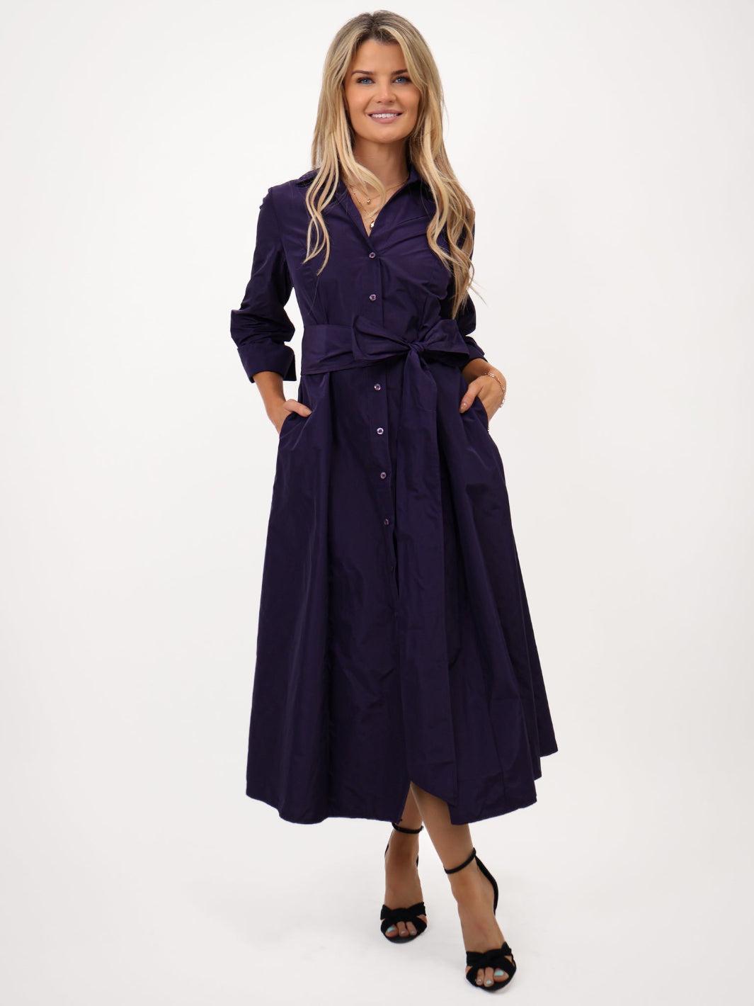 Woman wearing a dark purple dress with a belt on a white background