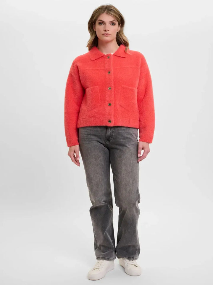 Woman wearing a bright red jacket and gray pants on a white background