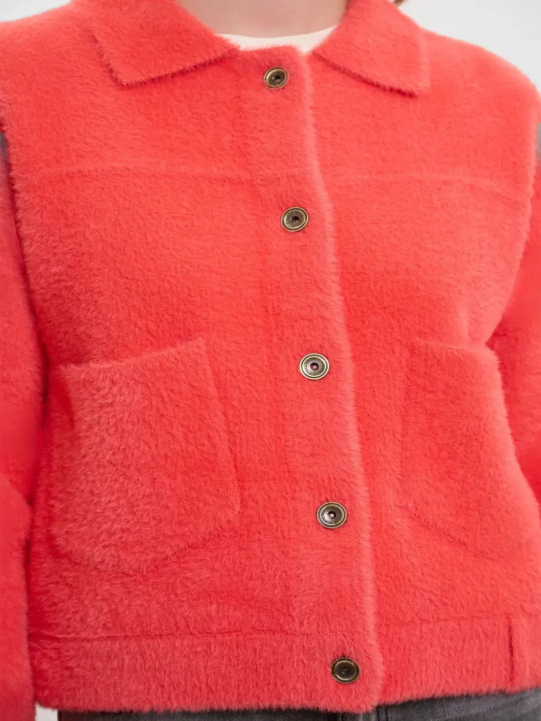 Close-up of a red textured jacket with buttons on a white background