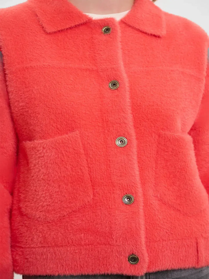 Close-up of a red textured jacket with buttons on a white background
