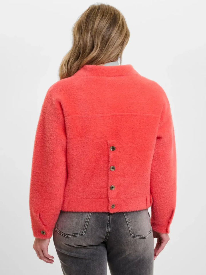 Person wearing a red textured sweater with button details on a white background