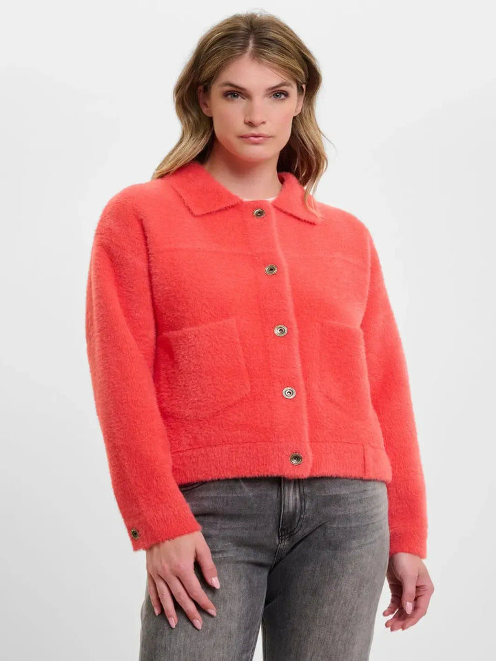 Woman wearing a coral jacket with a plain background