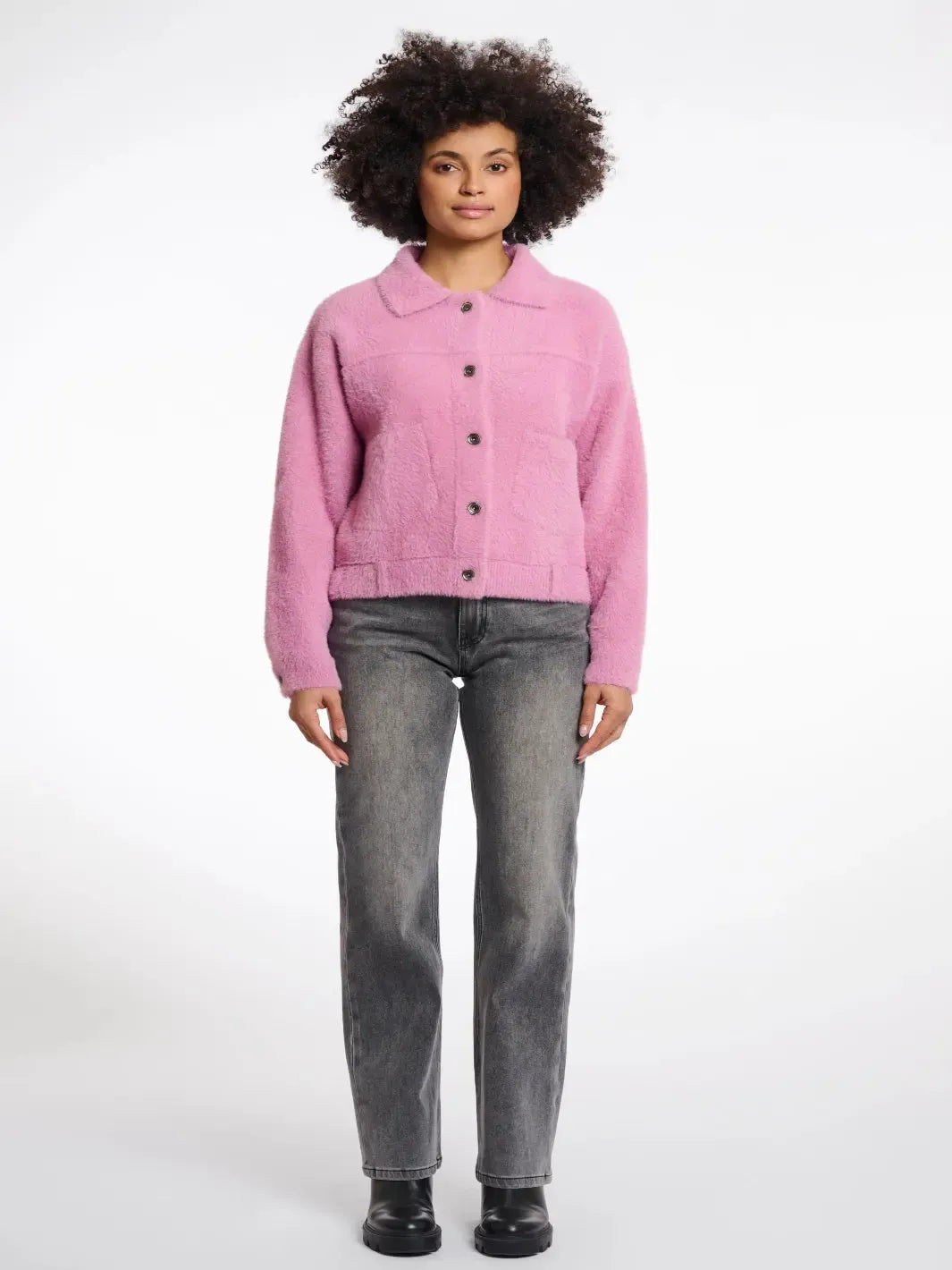 Person wearing a pink jacket and gray jeans on a white background