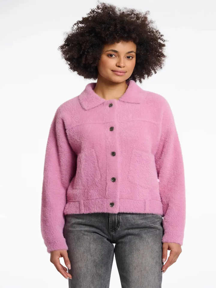 Person wearing a pink jacket with black buttons on a white background