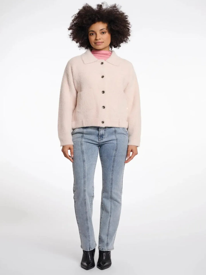 Woman wearing a light pink jacket and blue jeans on a white background