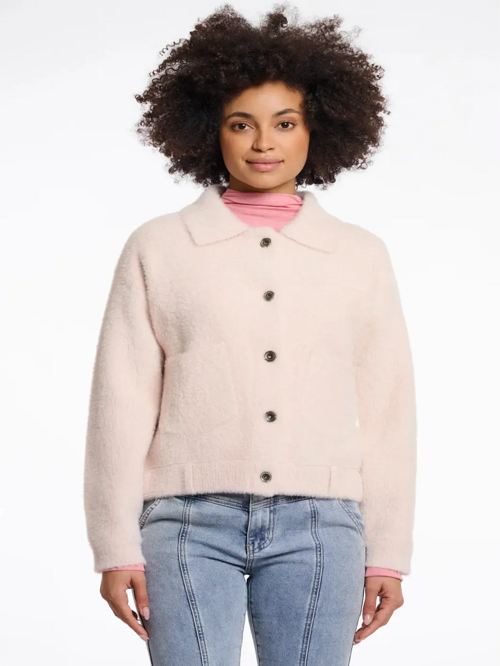 Woman wearing a light pink jacket with a white background