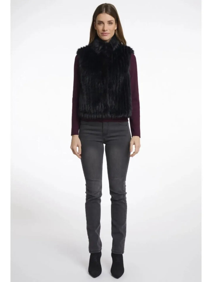 Woman wearing a dark fur vest over a purple top with gray pants on a white background