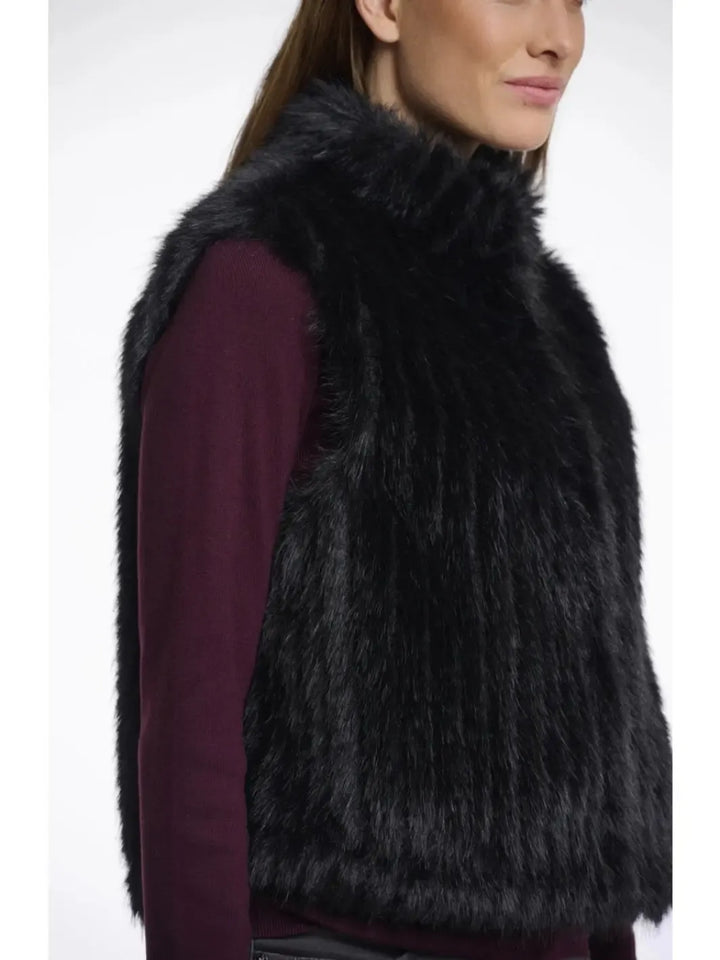 Black fur vest worn by a person on a white background